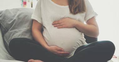 Embarazada sentada sujetándose la barriga