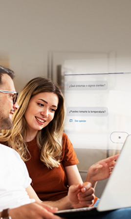 Dos personas sentadas revisando una información en un computador.