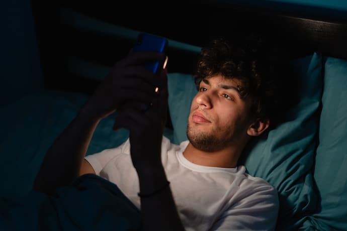 hombre viendo las redes sociales desde la cama