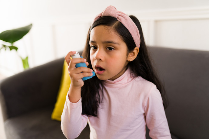 Niña con inhalador que sufre de asma infantil.