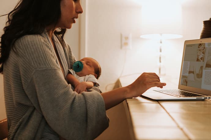 madre trabajando mientras cuida a su bebé