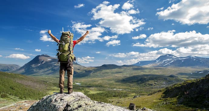 hombre en la cima de montaña luego de hacer trekking