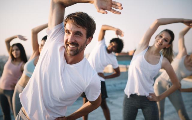 Grupo de personas jóvenes y deportistas haciendo estiramientos al aire libre