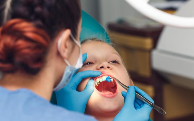 Dentista aplicando flúor en los dientes de un niño.