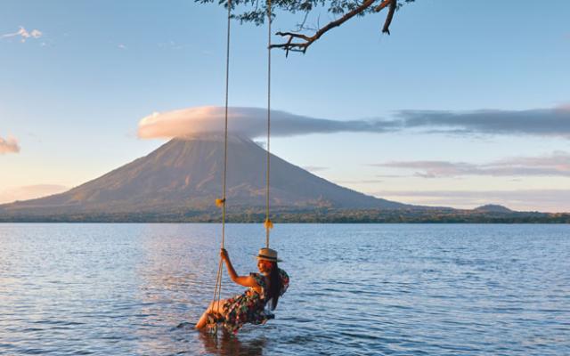 Mujer en columpio con vista al Volcán Ometepe, Nicaragua