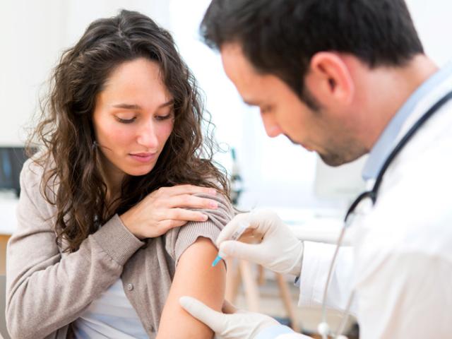 Médico poniendo una vacuna a una mujer joven